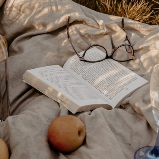 En opslået bog på et tæppe i det fri