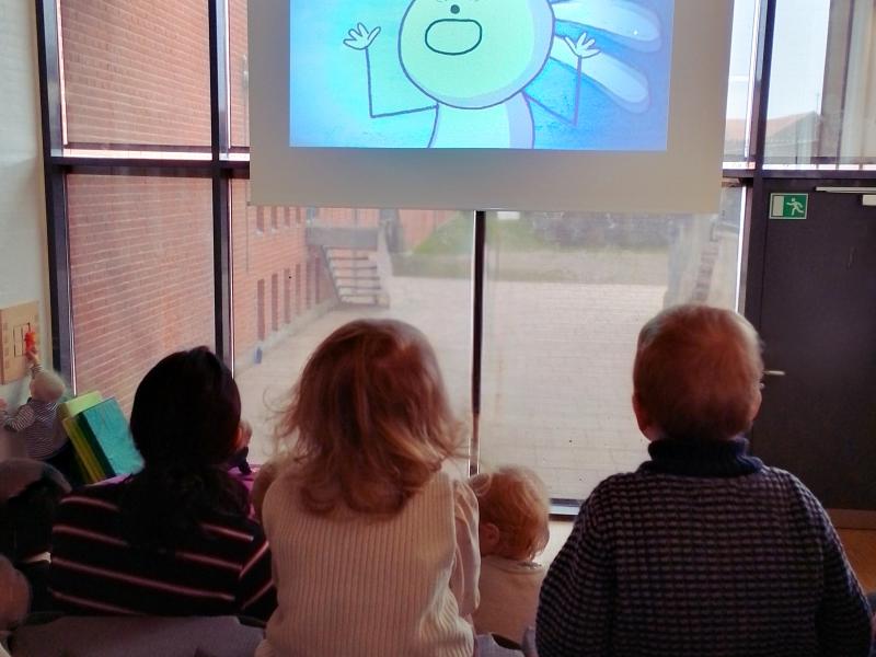 små børn med ryggen til ser film på stort lærred