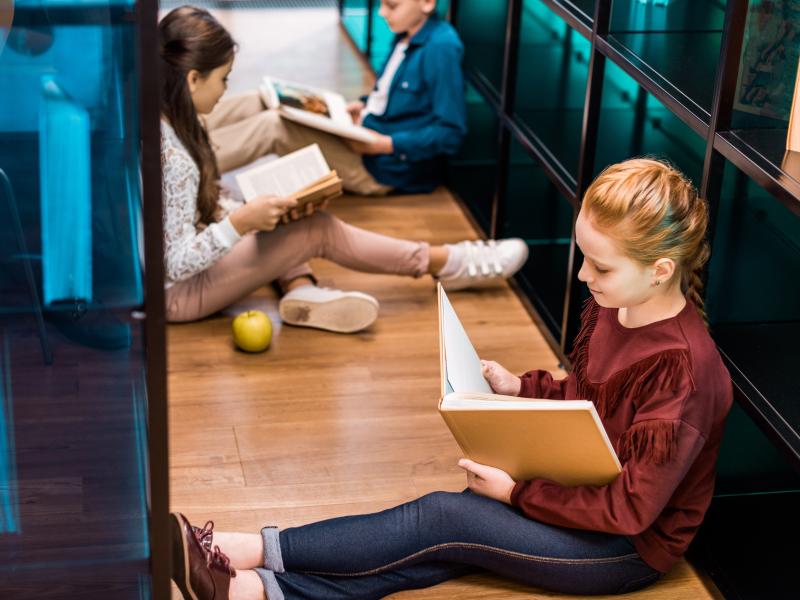 Elever læser bøger. Skoleklasse på biblioteket.