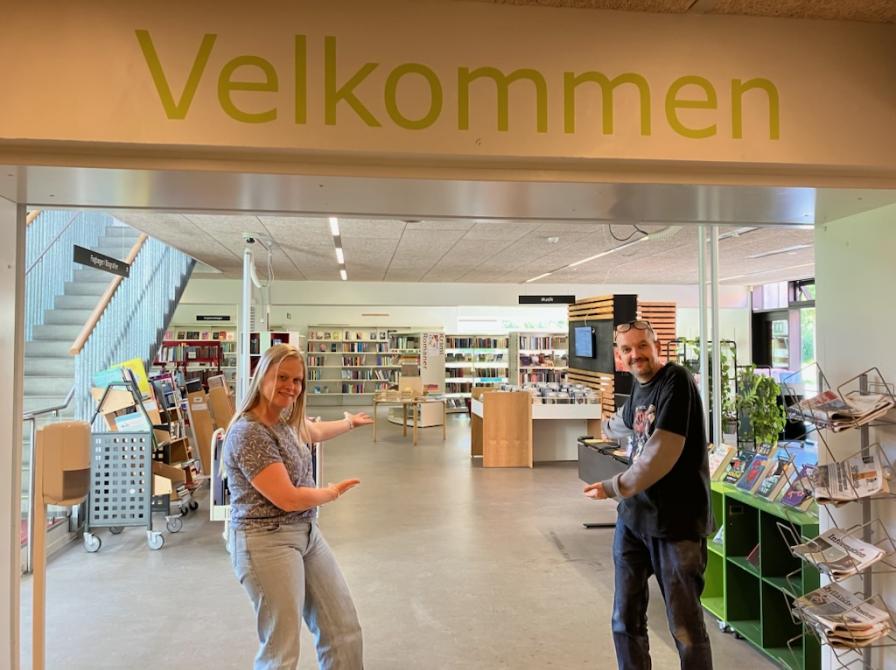 To bibliotekarer byder velkommen i Hasle Biblioteks indgangsparti